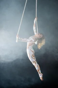 A young girl performs the acrobatic elements in the air trapeze. Studio shooting Stock Photos