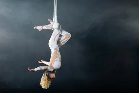 A young girl performs the acrobatic elements in the air trapeze. Studio shooting Stock Photos