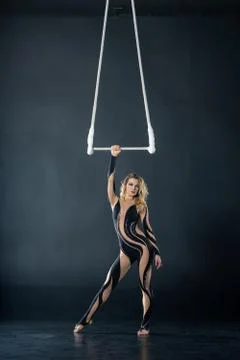A young girl performs the acrobatic elements in the air trapeze. Studio shooting Stock Photos