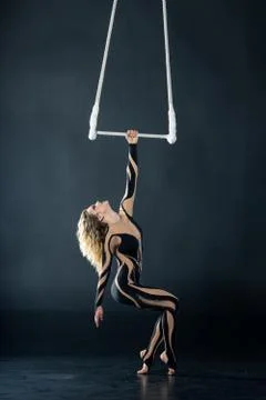 A young girl performs the acrobatic elements in the air trapeze. Studio shooting Stock Photos