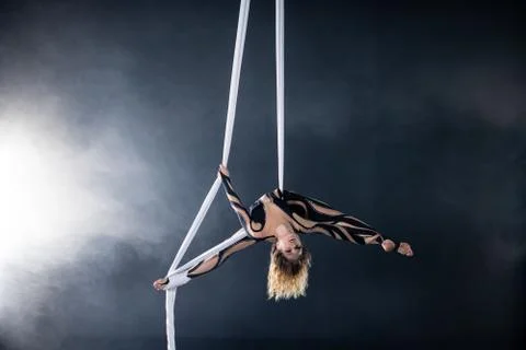 A young girl performs the acrobatic elements in the airrial silk. Studio Foto stock