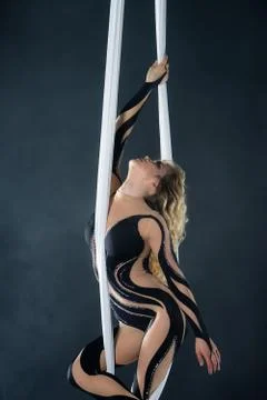 A young girl performs the acrobatic elements in the airrial silk. Studio Stock Photos