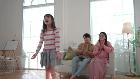 A young girl performs a dance for her parents in the living room Stock Footage 326281729
