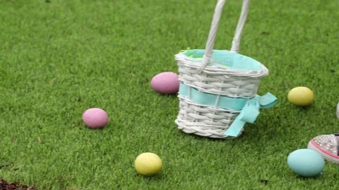 Young girl picking up Easter eggs in grass and putting them into basket Stock Footage 84300757