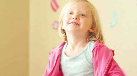 A young girl in a pink sweatshirt flexes her muscles Vídeo Stock 33871753