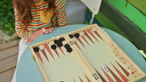 Young girl playing backgammon at home on a sunny day Stock Footage 290053549