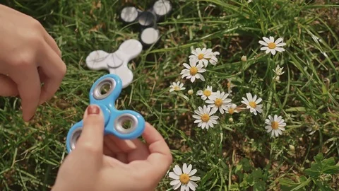 Young girl playing with a blue spinner on the lawn on a summer sunny day. Stock Footage