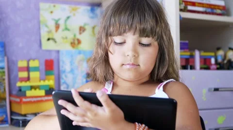 A young girl is playing a computer game on a digital tablet. Stock Footage 64659650