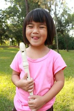 Young girl playing flute in park Stock Photos