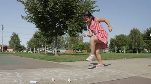 Young girl playing Hopscotch at park Stock Footage