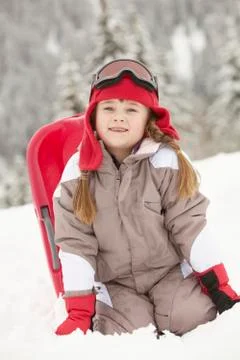 Young Girl Playing In Snow With Sledge On Ski Holiday In Mountains Stock Photos