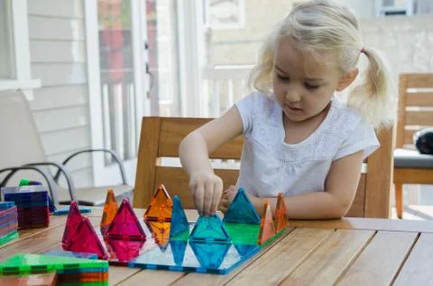 Young girl playing with triangular building shapes Stock Photos