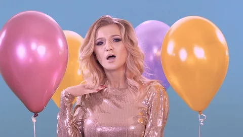 Young girl posing for the camera. Next to her balloons. Stock-Footage 99369514