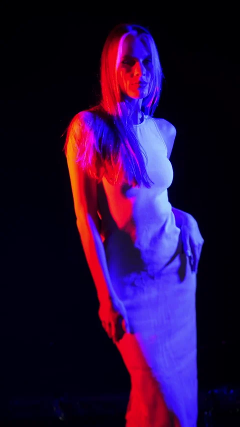 A young girl posing in a dark studio under neon light. Vertical video. Stock Footage 283802072
