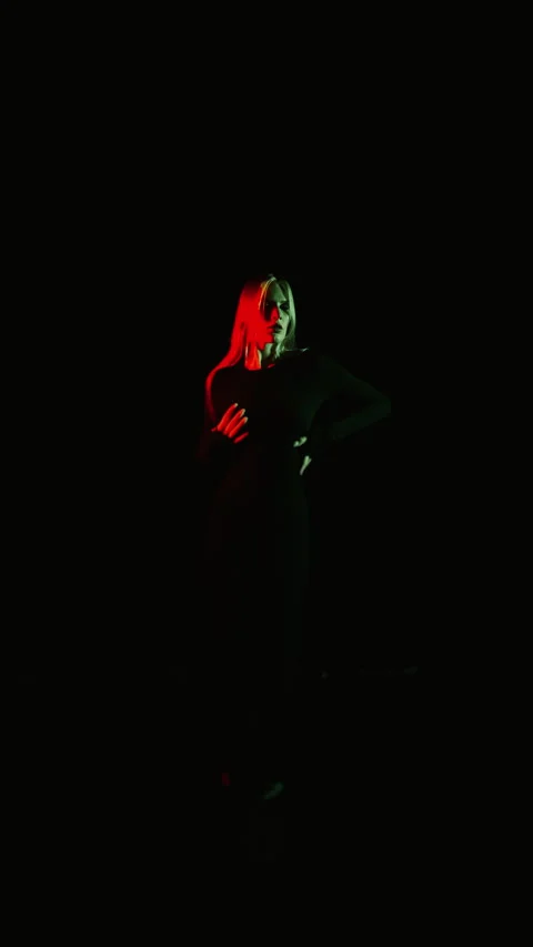 A young girl posing in a dark studio under neon light. Vertical video. Stock Footage 283802216