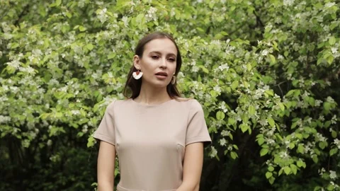 Young girl posing in front of a blooming garden, flowering Apple trees, summer , Stock Footage 108827436