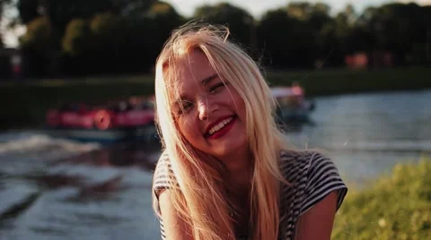 Young girl posing on the gren grass near the river at sunset close up look at Stock Footage 68380077