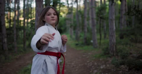 A Young Girl Practicing Dynamic Karate and Martial Arts Movements in a Peaceful Stock Footage 339500574