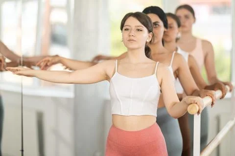 Young girl practicing second arm position holding by ballet barre 스톡 사진