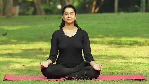 A young girl practicing Shitkari / Teeth hissing pranayama outside in a park Stock Footage 116087091