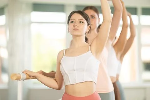 Young girl practicing third arm position holding by ballet barre 스톡 사진