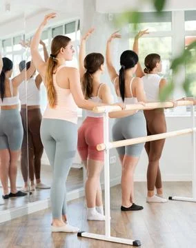 Young girl practicing third position holding by ballet barre 스톡 사진