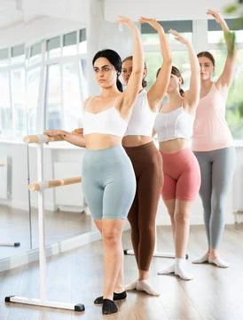 Young girl practicing third position holding by ballet barre 스톡 사진