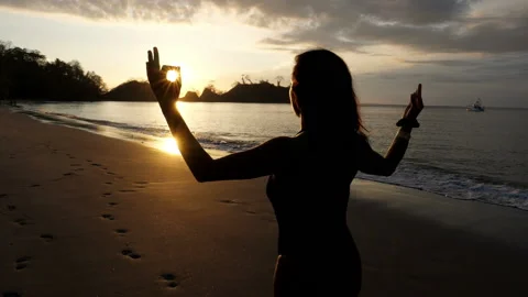 Young girl practicing yoga on the beach at sunset Stock Footage 106939719