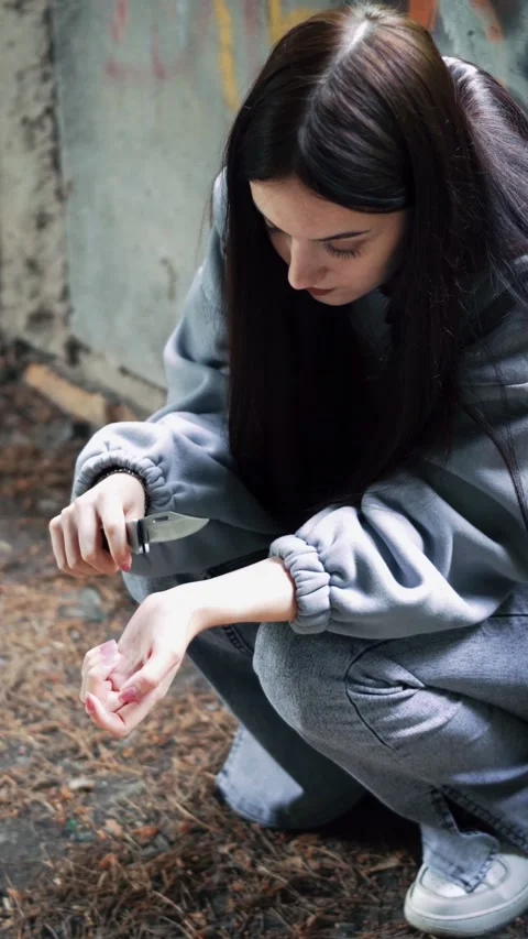 A young girl is preparing to commit suicide by cutting her wrists with a knife. Video stock 313171405
