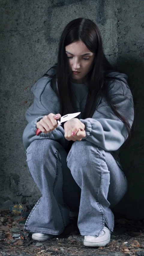 A young girl is preparing to commit suicide by cutting her wrists with a knife. Stock-Footage 313171432