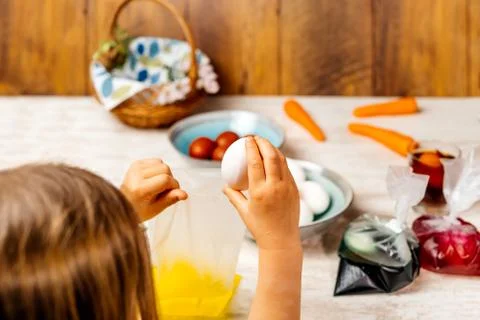 Young girl preparing Easter eggs for dying with food dye. Selective focus. Ea Foto stock
