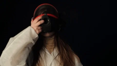 Young Girl put on full face respirarory mask and look at coronavirus mini model Stock Footage 127367461