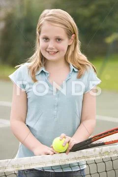 Young girl with racket on tennis court smiling Stock Photos