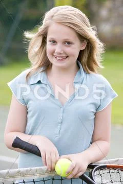 Young girl with racket on tennis court smiling Stock Photos