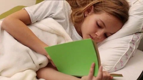 Young girl reading in bed Stock Footage 80115043