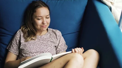 Young girl reading on couch Stock Footage 100049572