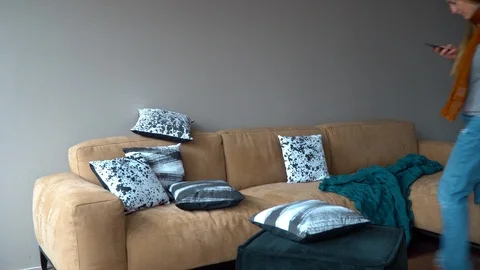 Young girl sat down on the couch and looks into the phone Stock Footage 91142453