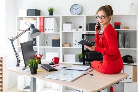 The young girl sat down on the table in her office, held a notebook in her... Stock Photos