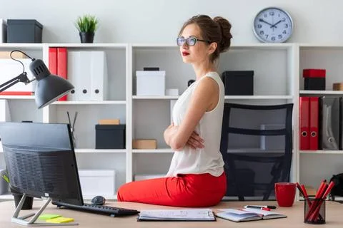 The young girl sat down on the table in the office. Beautiful young girl i... Stock Photos
