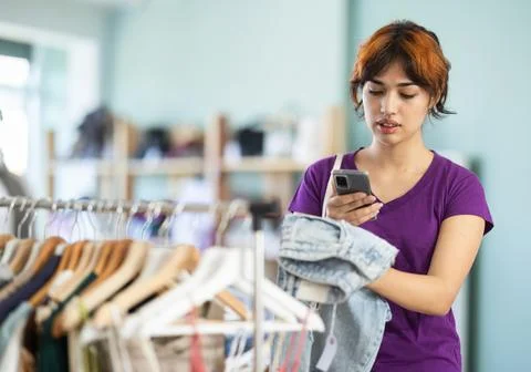 Young girl scanning QR-code on jeans pantaloons in clothing store Stock Photos