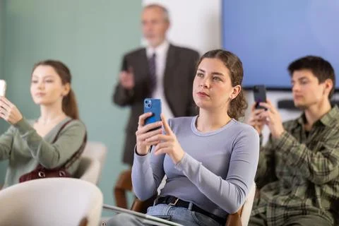 Young girl scanning QR-code with mobile devices during presentation Foto stock