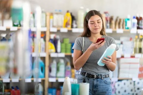 Young girl scanning QR code on shampoo bottle in personal care store 스톡 사진