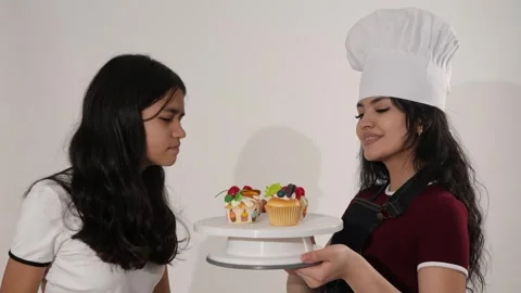 Young Girl Selecting and Tasting Cupcake Offered by Chef in Studio Vídeo Stock 346113143