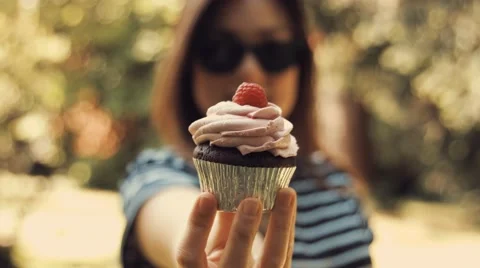 Young girl shows a nice raspberry cupcake in front of the camera Stock Footage 62978634
