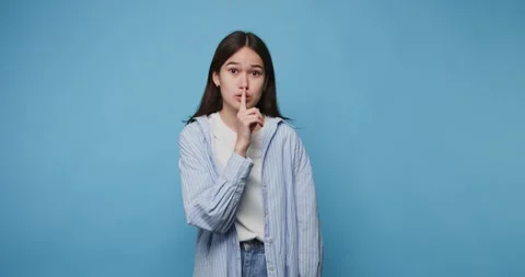Young girl with a shushing expression, placing a finger to her lips as if a.. Stock Footage 314336732