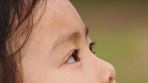 Young Girl Side Profile Looking Upwards in Soft Focus Outdoor Setting Stockbeeldmateriaal 334829964