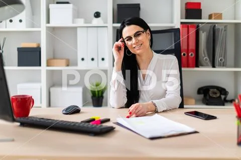 A young girl sits at a computer desk and holds one hand over the shackle of Stock Photos