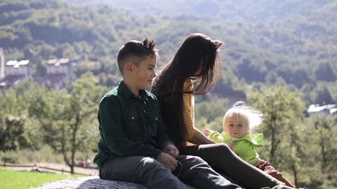 Young girl sits on haystack with two sons Stock Footage 128639451