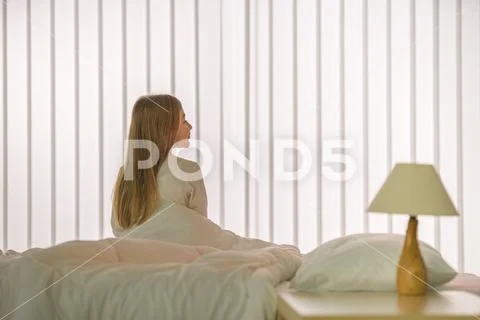 The young girl sitting on the bed Stock Photos