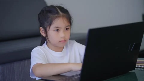 Young girl sitting at desk, using laptop computer, concentrated on screen, .. Stock Footage 337527229